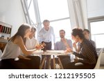 Cheerful diverse team people workers students laughing at funny joke while eating pizza together, friendly multi-ethnic colleagues group talking enjoying having fun and corporate lunch in office room