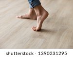Small photo of Side close up view of unrecognizable woman feet legs, barefoot girl standing indoors inside of modern home enjoy warm wooden heated floor, perfect groomed body part pedicure services spa salon concept