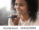 Smiling african woman holding phone speak activate virtual digital voice assistant on smartphone, happy black girl ask internet assistance service make call, easy mobile ai technology concept