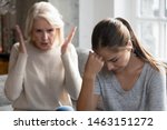 Small photo of Mid aged mother sit on couch scold grown up daughter, angry mum tell complaints lecturing teen adult child feeling stressed, misunderstandings, generational gap, difficulties in relationships concept