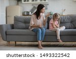 Small photo of Angry mother scolding little daughter people sitting on couch, parent teaches a naughty mischievous child, kid girl feels upset about punishment deprivation of entertainment due to misconduct concept