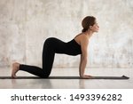 Small photo of Beautiful woman in black sportswear practicing yoga, standing in asana paired with Cat Pose on the exhale, Cow pose, Bitilasana exercise, attractive girl working out at home or in yoga studio