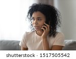 Small photo of Head shot portrait african focused on distant conversation by mobile phone 30s woman blab with boyfriend indoors, female sitting on couch at home solve formal or informal issues talking on cellphone