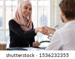 Happy asian muslim businesswoman hr manager employer wear hijab handshake hire male applicant make contract deal with partner collaborate shake client hand at job interview business meeting concept