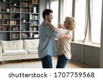 Small photo of Grown up son came to visit elderly mom, adult child and senior mum standing in living room dancing waltz, people enjoy warm communication having fun indoor, life value, time with aged parents concept
