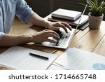 Close up businessman using laptop, typing on keyboard, sitting at wooden desk with documents, writing email, accountant writing financial report, busy student studying online, searching information