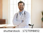 Portrait of smiling young caucasian male doctor wear white medical uniform, stethoscope and glasses look at camera posing in private clinic, happy man GP or show confidence at workplace in hospital
