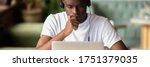 Small photo of Focused African student wear headphones studying on-line do exercise using laptop, watching video, learning language, self-education, e-study concept. Horizontal photo banner for website header design