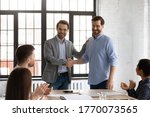 Small photo of Boss shake hands introduces new employee to members during briefing in board room, staff clap hands encourage newcomer welcoming express regard. Praise and appreciation, best worker of month concept