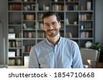Head shot handsome millennial 30s professional employee worker posing for camera at modern office. Business portrait, creative occupation person. Teacher, experienced business coach indoors concept
