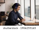 Small photo of Friendly polite hindu female in earphones client support manager look at laptop screen listen take note of customer complaint. Indian woman student talk to teacher at remote lesson in conference mode