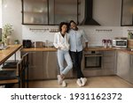 Full length portrait happy African American couple standing in modern kitchen at home, smiling wife and husband excited by relocation, satisfied clients purchased new apartment, mortgage concept