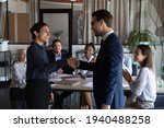 Small photo of Smiling diverse multiracial employees handshake close deal agreement at meeting. Happy multiethnic businesspeople shake hand get acquainted greet at briefing, congratulate colleague with promotion.