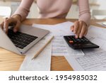 Small photo of Bookkeeping requires accuracy. Young woman hands typing on computer and digital calculator keyboards preparing electronic payments of utility bills counting taxes sum balancing accounts. Close up view