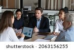 Small photo of Negotiations. Diverse business partners sit at conference table talk speak develop work strategy discuss stats information. Multiracial corporate employees meet at briefing share ideas set job targets
