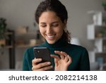 Small photo of Good virtual conversation. Smiling millennial latina lady touch smartphone screen text answer on friend message scroll social media networking. Happy young female online shopper buy goods in one click
