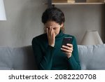 Small photo of Bad news on screen. Confused frustrated young latin lady cover face with palm turn away from cell seeing important call missed. Desperate millennial woman get message on phone about dismissal from job