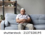 Small photo of Lonely thoughtful older 75s man sits alone on sofa thinking of loneliness, life or health problems. Melancholic senior lost in sad thoughts looks pensive, recollect past, suffers from solitude concept