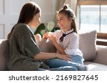Small photo of Happy young Caucasian mother and teen daughter sit relax on sofa talking sharing secrets. Smiling mom or nanny and teenage girl child rest on couch speak enjoy family weekend bonding at home.