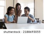 Small photo of Three multiracial colleagues use laptop speaking on project, discuss collaborative task, learn new software, enjoy amusing content during break at workplace. Teamwork, cooperation, modern tech