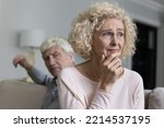 Small photo of Close up shot of sad disappointed unhappy older woman suffers from misunderstanding or resentment sit on sofa with frown angry husband after quarrel. Break up, divorce, emotional abuse, bad relations