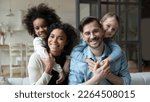 Small photo of Portrait of happy young multiethnic family with small diverse daughters relax in living room at home. Smiling multiracial mom and dad cuddle hug with adopted small girls children. Adoption concept.