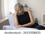 Small photo of Sad melancholic mature woman sit alone at home deep in thoughts, thinking about personal life troubles, unrealized goals, marriage split feel unhappy and lonely. Middle age crisis, divorce, nostalgia