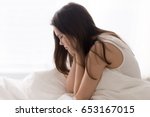 Tired after sleepless night young woman sitting in bed with head resting on hands. Lady stressed because of too early wakeup, suffering from lack of sleep. Female teenager hates to wake up at morning 