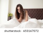 Exhausted sleepy young woman sitting in bed with messy hair, feeling drowsy after wake up too early in morning, sleepless night. Tired female teenager suffering of insomnia, lack of sleep or toothache