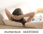 Relaxed woman lying on comfortable sofa on pillows with hands behind head in living room. Carefree lady resting at home or hotel, dreaming about happy future. Day off work concept. Close up. Rear view