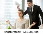 Calm attractive businesswoman practicing yoga at work, meditating in office with eyes closed, ignoring angry bad boss standing behind her back, avoiding negative people, positive thinking, no stress