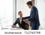 General manager presenting an envelope with premium or bonus cash to male company official. Boss congratulating happy employee with career promotion, thanking for good job and giving financial reward 