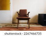 Old chair. Antique style apartment. House interior. Grunge furniture. Grandparents home lifestyle. Yellow glass door. Single chair isolated on wall.