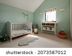 Small photo of Dry Drayton, England - August 2 2019: Childs bedroom space with cot, soft cuddly toys and shelved table.