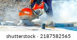 Small photo of Concrete cutting machine. A worker with a circular saw in the process of cutting, sawing granite, concrete tiles. New construction work on the repair, reconstruction of the pavement, road.