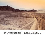 Safari and travel to Africa - extreme adventures or science expedition in a stone desert. Sahara desert at sunrise - mountain landscape with dust on skyline, hills and traces of the off-road car.