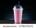 Diet Food and healthy nutrition. Pink Fruit smoothie, cherry milkshake in plastic glass on a dark background. cherry milkshake in takeaway cup