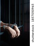 Small photo of hands of prisoner with handcuff in jail as background, hands in handcuffs behind bars, man in the handcuffs is behind the bar in the police station, prisoner concept