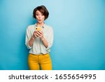 Photo of attractive lady hold telephone hands read new blog post comments not believe eyes speechless wear casual green shirt yellow trousers isolated blue color background