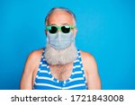 Small photo of Closeup portrait of attractive funky glad gray haired old man spend leisure pool party in spite of quarantine use protective medical face mask isolated blue background