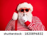 Small photo of Close-up portrait of his he nice handsome mysterious white-haired Santa wearing sunglasses showing shh sign silence silent mute isolated over bright vivid shine vibrant red color background