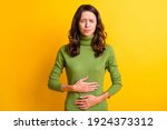 Photo of young unhappy unwell sick ill woman hold hand on stomach suffers pain pms isolated on yellow color background