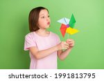Photo of young little girl blow windmill pinwheel rotate toy isolated over green color background