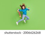 Full length photo of brunette ponytail haired girl jump wear jeans hold longboard fly hair isolated on green color background