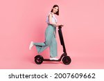 Full size profile side photo of young girl happy positive smile driver trip weekend scooter isolated over pink color background