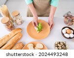 Top angle cropped photo of grandmother prepare homemade meal breakfast put salad lettuce on bread delicious sandwich at home