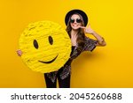 Photo of cheerful positive happy lady point finger smile hold hand emoji paper pinata isolated on yellow color background