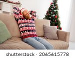 Photo of good mood relaxing smiling male wear ugly red sweater sit sofa enjoying free time celebrate new year merry christmas at home
