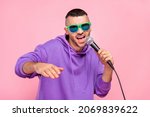 Small photo of Photo of cool young brunet guy sing in mic wear eyewear hoodie isolated on pink background