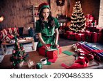Portrait of attractive focused wavy-haired girl elf preparing gift eve writing greetings at home modern loft industrial interior indoors